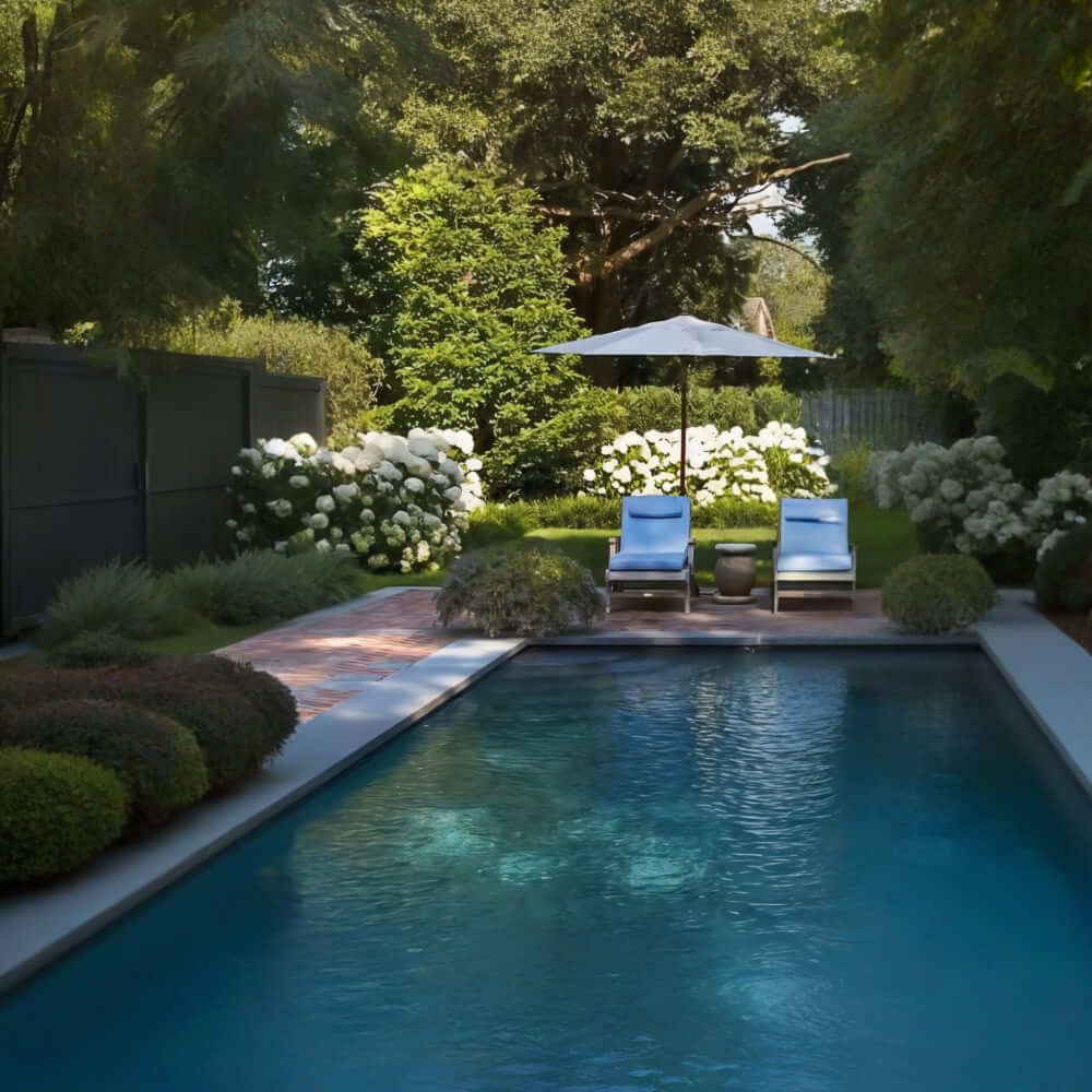 La nostra azienda progetta aree esterne intorno alle piscine, incorporando elementi come un patio in pietra con due lettini e un ombrellone. L'area è circondata da una vegetazione lussureggiante e fiori bianchi, che conferiscono al giardino un'estetica classica e rilassante. Il nostro obiettivo è quello di creare un ambiente armonioso che inviti al relax, nel rispetto della storia e del carattere senza tempo del luogo.